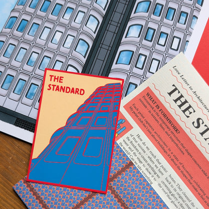 Promotional materials for 'The Standard' with building illustration and text on a wooden surface.